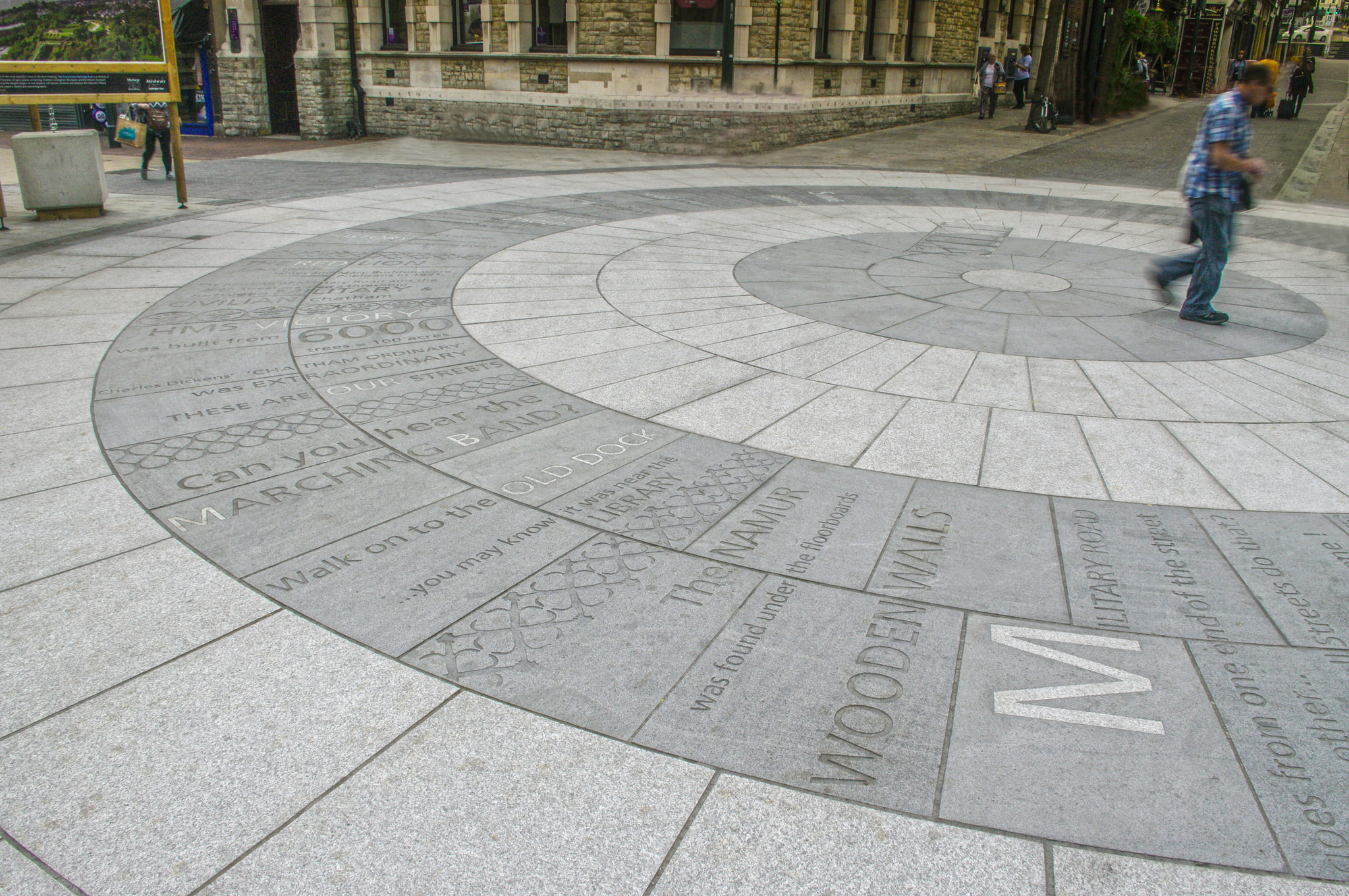 Circular granite feature artwork showing light and dark grey granite with embedded and sandblasted text and pattern work